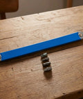 Badass Offset Extension Wrench With Swappable Drive Adapters And Quick Socket Attachments Built From Tough High Carbon Steel No Hustle Multi Tool For Cramped Spaces Or Gunked Up Bolts Orange, blue handle with adapters on a wood table.
