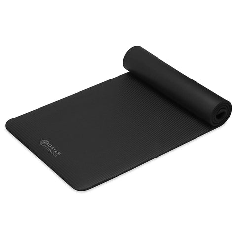 Killer 10mm Thick Yoga Mat With Big Time Cushioning Plush NBR Foam Joint Relief For Beginners Pilates Stretching Floor Workouts Includes Cinch Strap Black rolled yoga mat on gym floor.