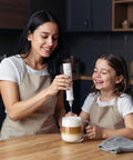 Rechargeable Milk Frother Handheld Foam Maker With Stainless Whisk For Cappuccino Latte Bulletproof Coffee Keto Diet Protein Powder Matcha Pure White Two Whisks No Fuss Quick Froth used by woman and child in kitchen