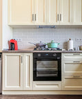 Modern kitchen with cream cabinets, integrated oven, washing machine, and counter appliances, featuring sleek drawer handles.