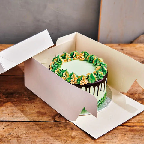 Top Tier White Cardboard Cake Box With A Slick Separate Lid And Fully Foldable Sides Heavy Duty Reusable Bakery Carrier holding a decorated cake.
