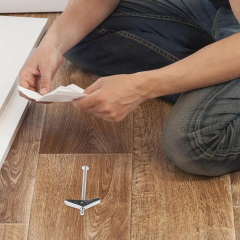 Person preparing to use 24 Piece Galvanized Steel Toggle Bolt Kit For Drywall Heavy Duty Anchors With Wing Nuts on wood flooring