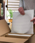 Person using Heavy Duty Foam Wrap Sheets And Pouches 80 Count Mixed Sizes for packing fragile items in a box.