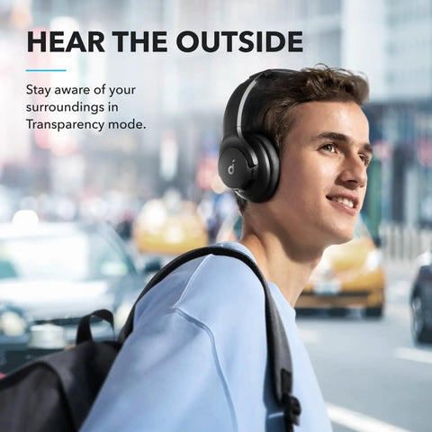 Person wearing Q20i Hybrid Active Noise Cancelling Wireless Over Ear Headphones With 40 Hour Battery Life Dope Bass Rich Hi Res Audio App Customization Transparency Mode Black in city setting.