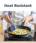 Heat resistant Top Shelf Silicone Spatula Set Five Piece Kit being used to stir vegetables in a black skillet.