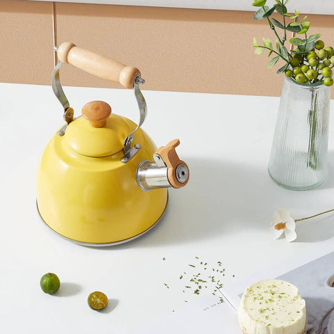 Yellow 1.6 Quart Tea Kettle With Cool Touch Wooden Handle Food Grade Stainless Steel Stovetop Teapot Whistling Kettle For Easy Pour Ergonomic Grip Safe Heat Resistant Kitchen Accessory displayed on a kitchen table.
