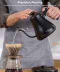 Man pouring water with a Smart Electric Kettle With WiFi And Alexa Control For Home Baristas Gooseneck Pour Over Kettle With Variable Temperature 1200W Quick Heat 0.8L Capacity One Hundred Percent Stainless Steel Matte Black into a coffee dripper.