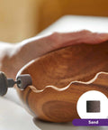 Rotary tool with sanding drum smoothing a wooden bowl; side-angle close-up