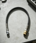 Heavy Duty 4500 PSI High Pressure Air Hose With Anti Kink Design and Solid Brass Steel Fittings. Close-up view on a workshop table.