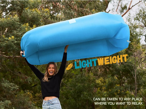 Person outdoors holding a blue Inflatable Couch Air Lounger Chair For Camping And Beach Trips Portable Blow Up Sofa, trees in background
