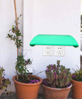 Rainproof Abs Ev Charger Cover Built For Tough Outdoor Environments on wall above potted plants, providing weather protection.