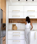 Talentedeco 10 Pack Brushed Gold Kitchen Cabinet Pulls in modern kitchen with white cabinets and wood elements.