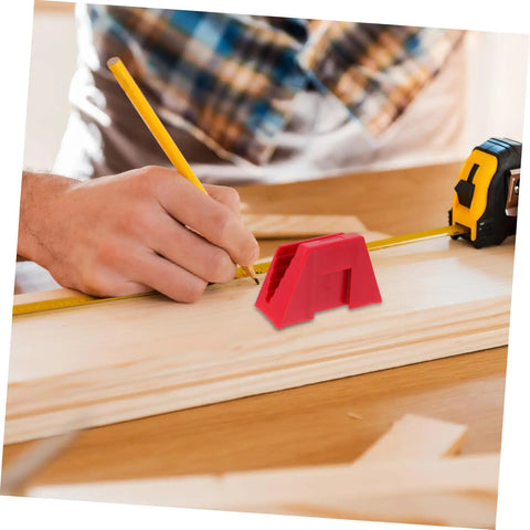 Person using a tape measure and pencil for woodworking near a red tool on a wooden board in a workshop setting.