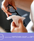Lens cleaning wipe being used to clean eyeglasses; white disposable wipe held by hands.