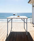 34-Inch Square Folding Table With Carrying Handle on beachside deck, fold-in-half design, heavy duty HDPE construction, supports 330 lbs