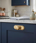 Champagne Bronze Cabinet Knobs With Orbit Rim Backplate Beaded Pull on navy cabinet against marble countertop