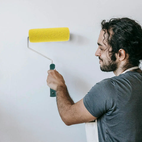 Person using a yellow Texture Pattern Paint Roller Sponge Brush For Walls Ceilings And Home Painting for wall painting.