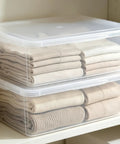 Heavy Duty Clear Plastic Storage Bins Are The Real Deal With Secure Snap Top Lid Stackable Under Bed Totes 28 Quart low profile bins organizing folded clothes on a shelf.