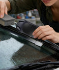 Person using Windshield Wiper Repair Tool Quick Fix Automotive Restorer For Cars Slick Squeegee Edge Refresher on wet windshield.