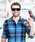 Welding Safety Goggles Offering A Badass Level Of Protection With An Over Glasses Design Delivering Crystal Clear 180 Degree Vision So You Can See Every Detail With Ease And Comfort Using High Quality Materials To Keep You Safe And Secure During Work, worn by a man holding a cordless drill.
