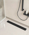 24 Inch Linear Shower Drain Tile in Grate Matte Black Floor Drain Kit No Flange installed in contemporary bathroom setting.