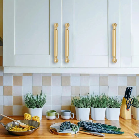 10 Pack 5 Inch Hole Center Brushed Gold Cabinet Pulls on white cabinets in modern kitchen with greenery and cookware.