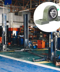 Heavy Hitter Cast Iron Pillow Block Bearing Kit Featuring Dual Bolt Flange Housing And Compact Two Hole Design For Cramped Workspaces And Daily Factory Production Lines displayed in a warehouse with equipment.