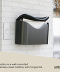 Postino Wall Mount Mailbox In Black With Hinged Lid And Weather Resistant Stainless Steel on white brick wall