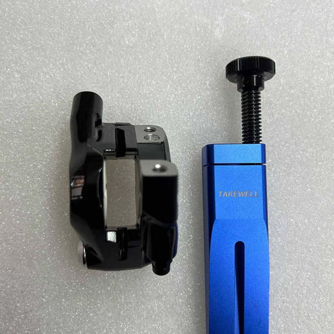 Blue aluminum Piston Press Tool for Brake Calipers next to caliper, Universal Bicycle Hydraulic Disc Brake Piston Tool.