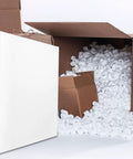 Two Pack High Density Polyurethane Foam Sheets Cuttable Moving Pad resting beside cardboard boxes filled with packing peanuts.