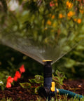 Three Pack Multi Adjustable Spike Sprinklers With Quick Connect Bundle in use on a garden bed, black grey yellow, hose ready.