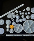Knockout Bundle Of 34 White Plastic Rack And Pinion Gears With Worm Gear Reducer And Pulley System For Diy Mechanical Projects Student Friendly Science Engineering Builds, assortment on black background.