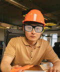 Heavy Duty Welding Safety Glasses Featuring Over Glasses Compatible Design worn with orange helmet, ideal for protection from sparks.