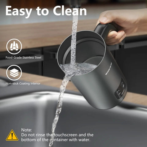 Cleaning the 4 In 1 Milk Frother And Warmer With Stainless Steel Build And Touch Screen under running water in a kitchen sink.