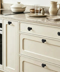 Slick Matte Black Cabinet Knobs Heavy Duty Zinc Alloy on cream kitchen drawers, smooth grip, easy install, solid wide base.