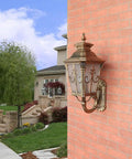 Rustic Exterior Wall Lantern Heavy Duty Outdoor Light Fixture For Front Porch Durable All Weather Barn Style Sconce With Solid Antique Brown Finish mounted on a brick wall.