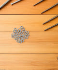 One Hundred Pack Stainless Steel Eyeglass Flat Washers For Glasses Frame Repair Kit Screw Gaskets arranged on wooden surface.