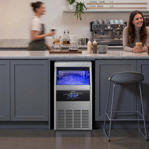 Rock Solid Commercial Ice Maker, Drip Free Self Cleaning LED Interface With Up To 130 Lbs Daily Production And Super Roomy 30 Lb Storage Bin, Undercounter Stainless Steel Gear For Home Bars in a modern kitchen.