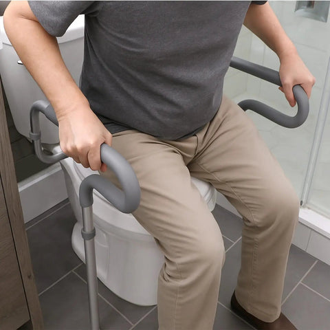 Solid Adjustable Toilet Safety Rails For Seniors Offering Smooth Bailout Support With Non Slip Padded Arms Heavy Duty 300 LB Capacity Top Shelf Bathroom Assist Bars Commode Seat Frame close-up of person using toilet safety rails