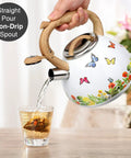 Stovetop Tea Kettle With Wood Pattern Handle, Loud Whistle, 2.7 Quart Food Grade Stainless Steel Pot For Induction And Gas Stoves, Butterfly Design, Rust Resistant, Easy Pour Tea Maker pouring into glass
