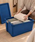 Massive 45 Gallon Rolling Storage Tote With Easy Glide Wheels To Tackle Heavy Hauling Tasks Without Breaking A Sweat Plus Stackable Design For Sweet Organization Solutions In Blue filled with neatly rolled blankets.