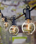LED Outdoor String Lights 109 Ft With 52 Edison Shatterproof Bulbs Plus 2 Spares, Dimmable, hanging in a garden