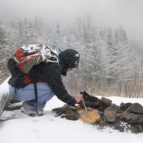Person using Six Pack Natural Jute Fire Starters For Quick Ignition Outdoor Camping Survival Tool For Easy Fires in snowy forest.