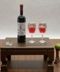 Hella Cool Miniature Red Wine Bottle Set Featuring Two Resin Filled Wine Glasses And A Static Corkscrew For Dollhouse Decor on table
