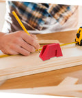 Person using red carpenter's square tool with tape measure on wooden board during woodworking project