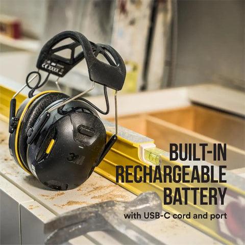 WorkTunes Connect Wireless Hearing Protector With Bluetooth Technology 26 DB Noise Reduction Rating Dope Sound Quality and Safe Volume Control for on-the-job use, shown on a workbench with built-in rechargeable battery.