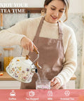 Woman pouring hot water from Stovetop Whistling Tea Kettle Two Point Seven Quart Floral Pattern Stainless Steel Tea Pot With Wood Pattern Handle Perfect For Boiling Water Coffee Or Milk Durable All Stovetop Kitchen Must Have For Real Essential into a glass.