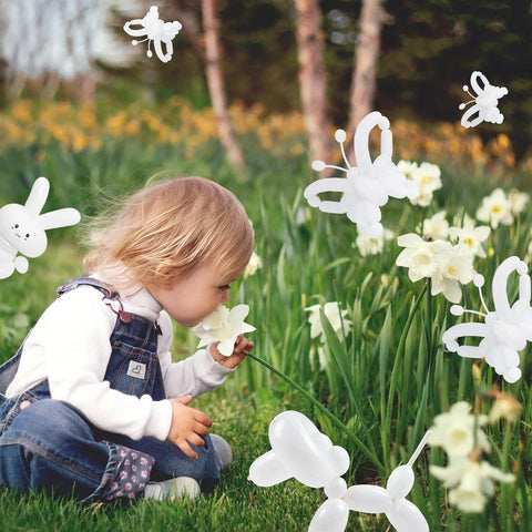 Child smelling a flower with whimsical balloon animals, showcasing 100 Pcs Clear Long Latex Model Balloons No Fuss Twisting Surface Prime Grade Heavy Duty Rubber For Kids Party Carnival Decor And Big Time Sculpture Art Projects.