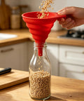 Four Pack Foldable Silicone Funnels Designed To Ditch The Drips And Streamline Liquid Transfers Between Kitchen Bottles Home Bars And Road Trip Gear For A Hassle Free Pour Every Single Time, red funnel pouring seeds into a glass bottle.