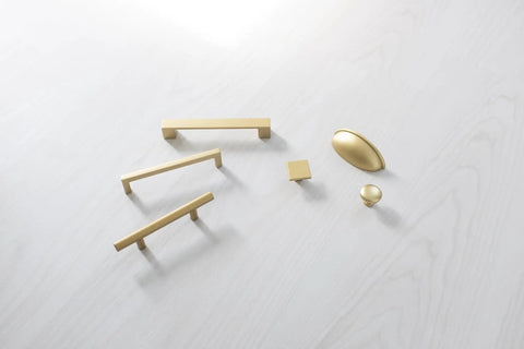 10 Pack 3-Inch Center Cabinet Handles with Brushed Brass Finish displayed on a light surface, showcasing various styles and shapes.
